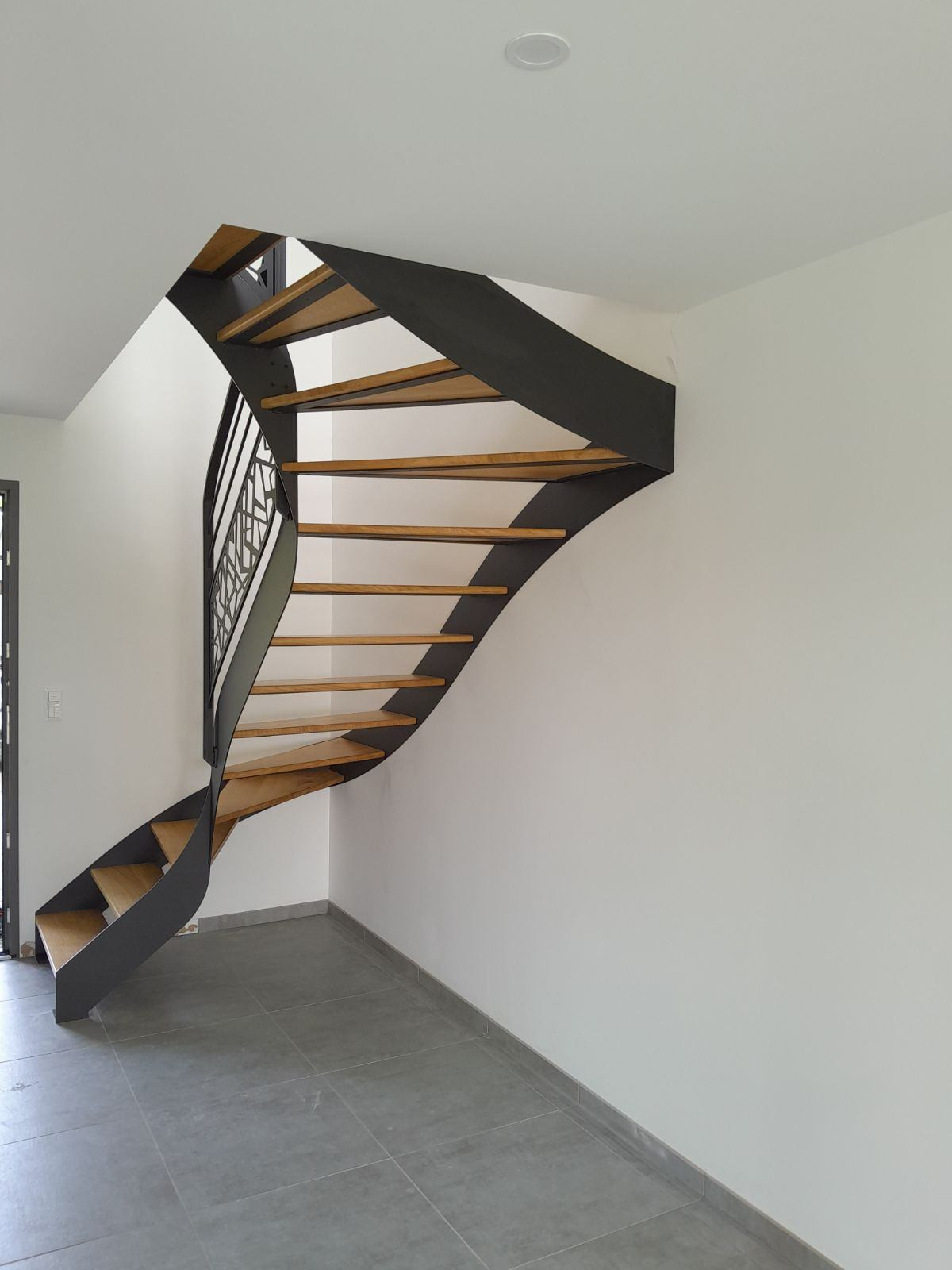 Escalier double limons 2/4 tournant en acier Marche en chêne Garde corps en acier, cadre en tube 40x20mm, 2 lisses 12x12mm, soubassement en tôle décorative "cardiaque" Triangulation, remplissage en tôle décorative "cardiaque" Laquage ral noir 2100 sablé 53100 MAYENNE