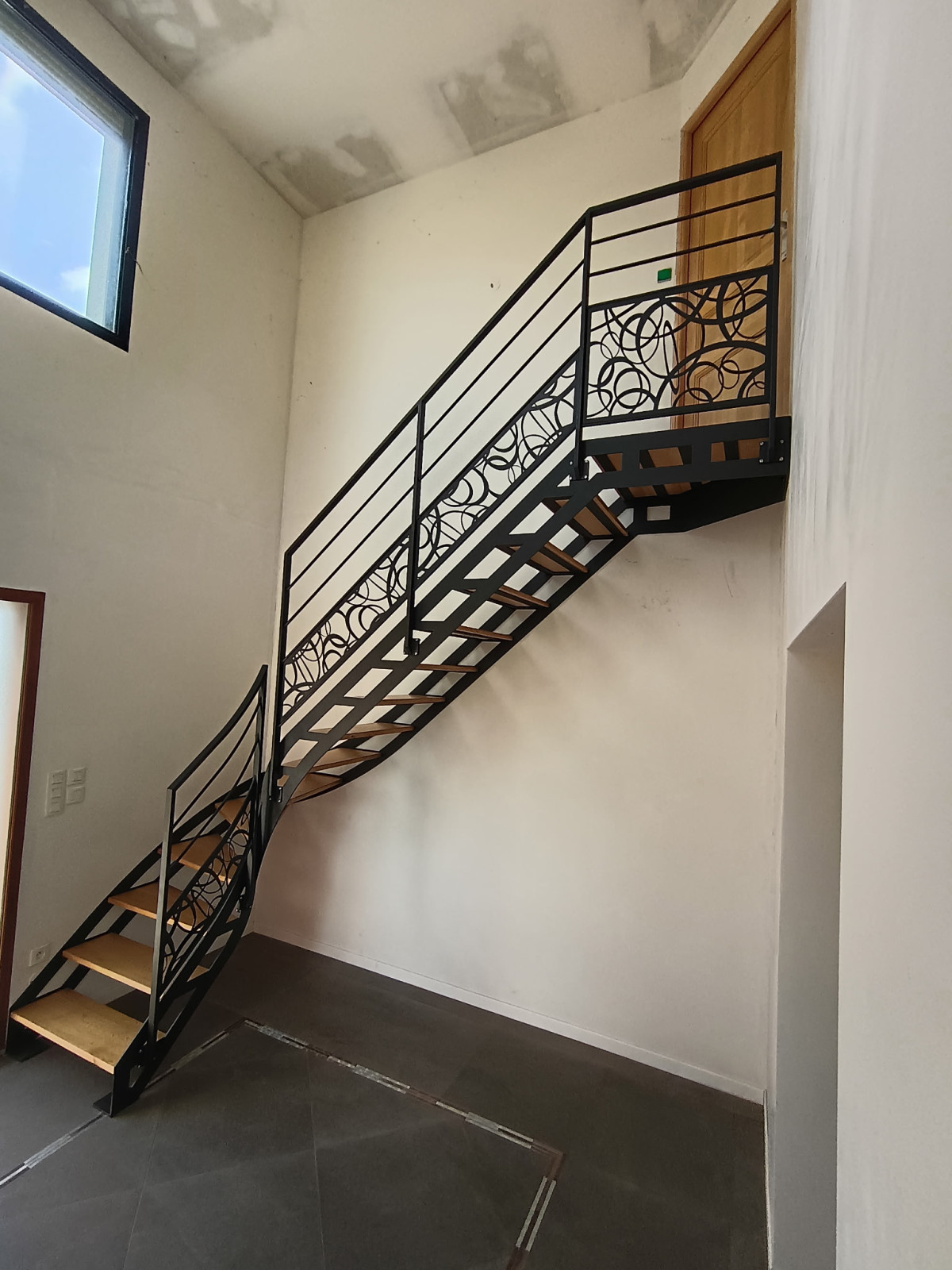 Escalier doubles limons 1/4 tournant, limon découpe laser. Marches en chêne + palier Garde corps, ossature en cadre, 2 lisses, soubassement en habillage décoratif "ovales décalé" Laquage ral noir 2100 sablé 53480 ST GEORGES LE FLECHARD