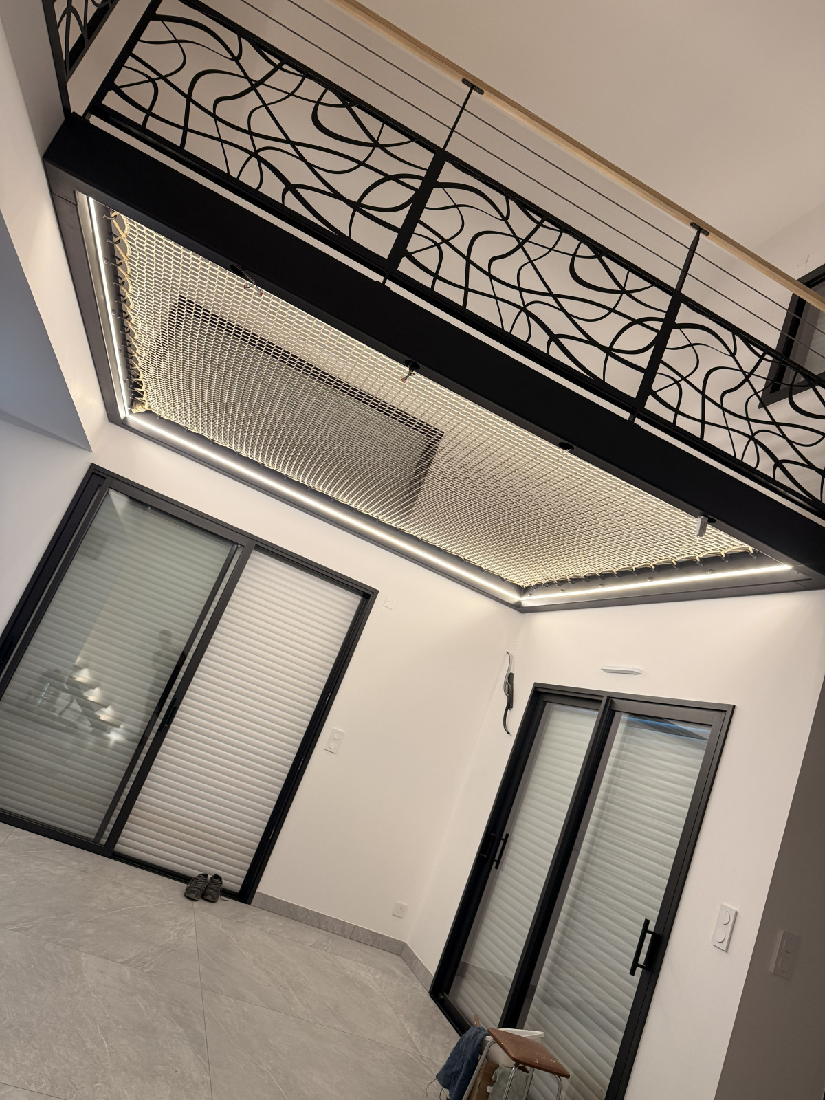 *Escalier limon central 1/4 tournant en acier Ruban Led dans profil d'encastrement avec capotage pvc opaque Garde corps en acier, ligne de câble, soubassement en habillage décoratif "spline" Laquage ral noir 2100 sablé *Ossature vide sur sejour en tube, laquage ral noir 2100 sablé Remplissage en filet d'habitation maille 30x30 tressé couleur beige 53100 Moulay