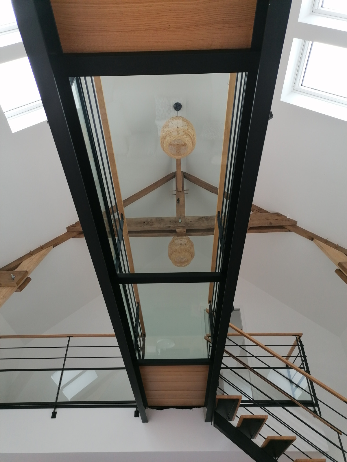 Passerelle, remplissage en chêne vitrifiées style parquet et dalle de verre clair, garde corps en acier, poteaux plats, 2 lisses D.13, soubassement vitrage+pareclose, main courante 50x30 en chêne, laquage ral 9005 Fine Texture, 53210 LOUVIGNE.