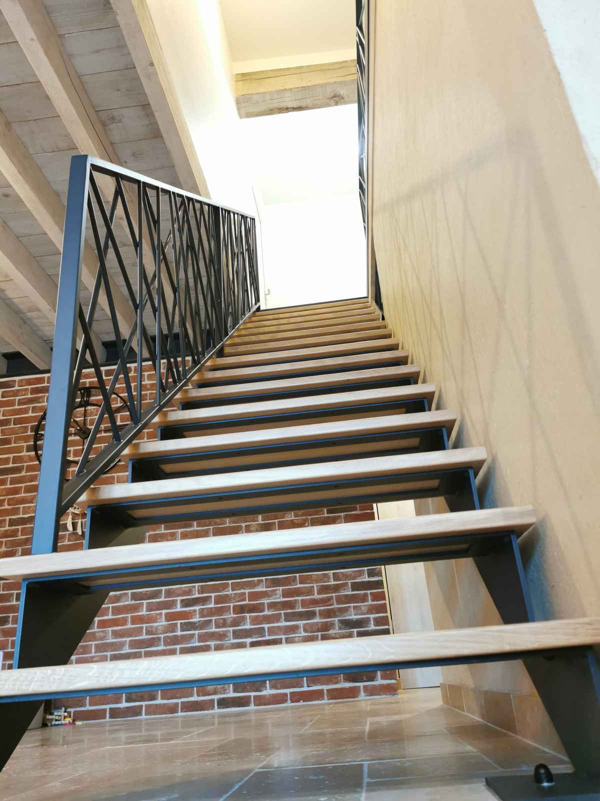 Escalier droit en acier, double limons crémaillère, marches en chêne vitrifiée 2 couches, garde corps en acier, ossature en cadre 40x20mm, remplissage en lisses D.13 entremêlées, laquage ral noir 9005 FT.