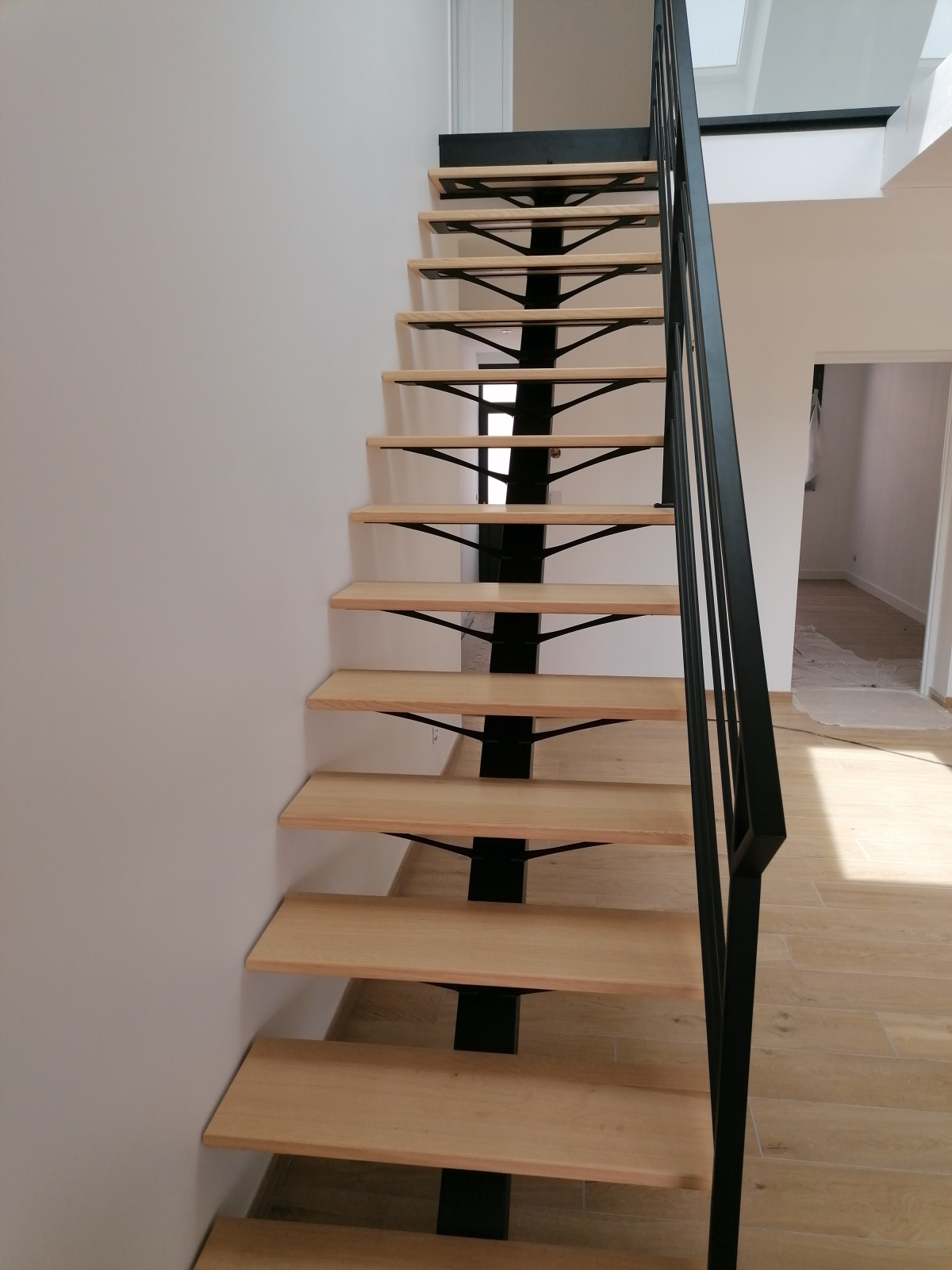 Escalier droit en acier, limon central, marche en chêne vitrifiée 2 couches, Garde corps en acier, poteaux plats, 4 lisses D.13, main courante en acier 50x30mm, laquage ral noir 9005 FT.