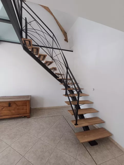 Escalier limon central 1/4 tournant débillardé, marches en chêne rustique sablé, laquage ral 2100 sablé Garde corps poteaux plats, remplissage lisses D.10 cintrées, main courante 40x10, laquage ral 2100 sablé Ossature en UPN, remplissage en dalle de verre clair, laquage de l'ossature ral noir 2100 sablé 72170 SEGRIE
