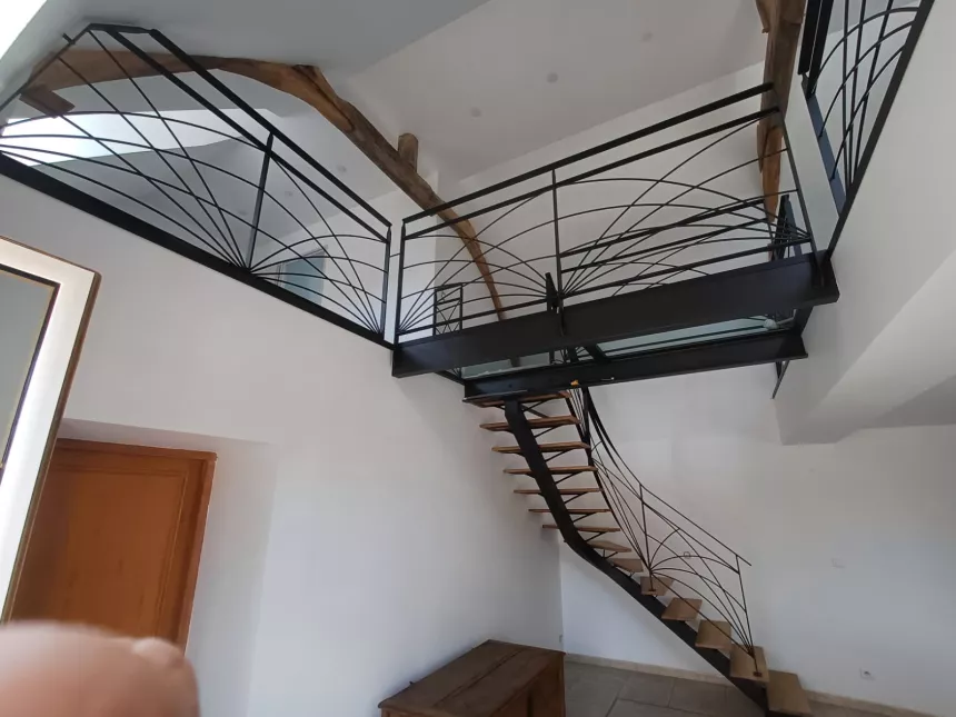 Escalier limon central 1/4 tournant débillardé, marches en chêne rustique sablé, laquage ral 2100 sablé Garde corps poteaux plats, remplissage lisses D.10 cintrées, main courante 40x10, laquage ral 2100 sablé Ossature en UPN, remplissage en dalle de verre clair, laquage de l'ossature ral noir 2100 sablé 72170 SEGRIE