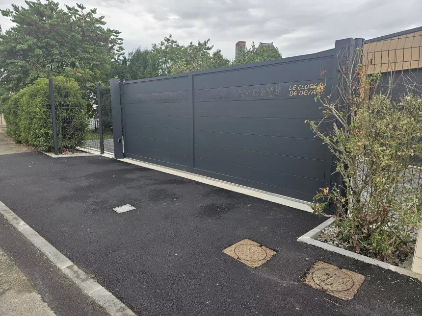 Portail coulissant en aluminium, remplissage en lames avec un habillage décoratif "fleurs" + inscription adresse. Laquage ral 7016 FT 53600 CHATRES LA FORET