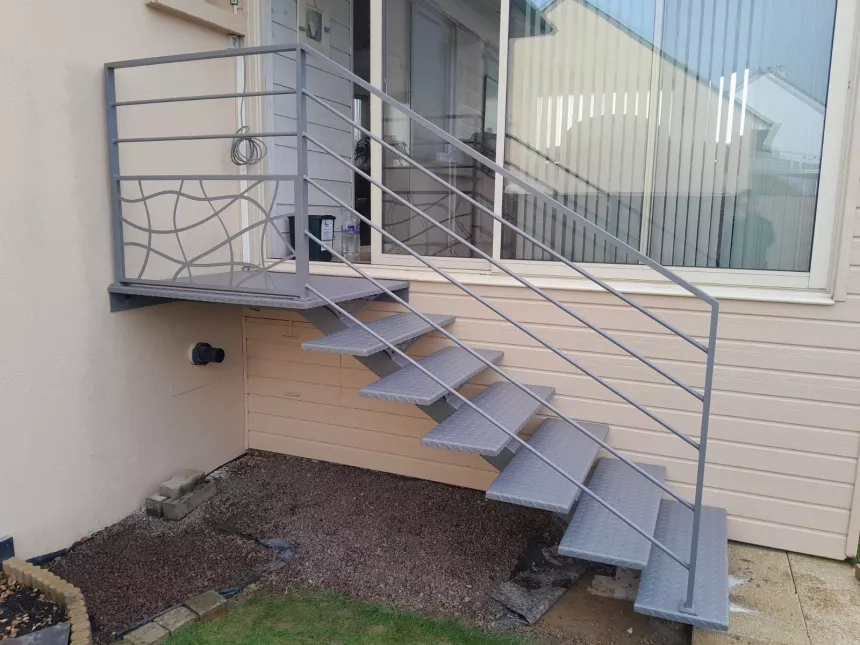 Escalier extérieur 6 marches + 1 palier. Marches en acier larmés. Garde corps en aluminium, cadre 40x20mm, remplissage en lisses D.16 + soubassement habillage décoratif "spline" sur le garde corps droit. 53810 CHANGE