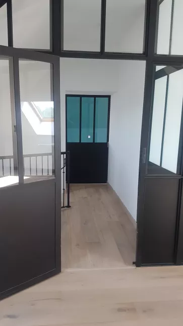 Cloison verrière en acier + porte ouvrante, avec traverse intermédiaire, soubassement en tôle, verre clair en 33/2 feuilleté, laquage ral noir 9005 FT. 53150 ST CHRISTOPHE DU LUAT.