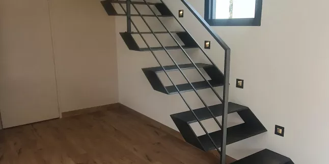 Escalier 1/4 tournant en acier, limon porteur latéral, marche en acier caissonné, épaisseur 12mm, garde corps en acier, cadre en tube 12x12mm, laquage ral noir 2100 sablé. 53810 CHANGE.