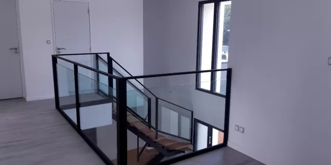 Escalier limon central 1/4 tournant, sabot 41, laquage ra 9005 ft, marches+ double marche style podium en chêne, garde corps en acier, cadre en tube 50x30, remplissage en vitrage fixé dans cornière+ pare close. 53000 LAVAL