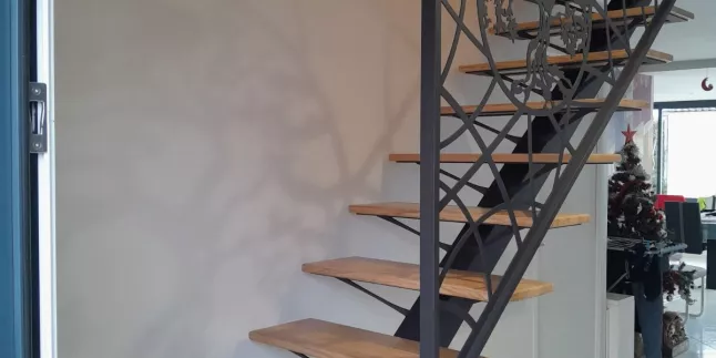 Escalier limon central, 1/4 tournant, en acier Triangulation en habillage décoratif "courbes+arbre de vie" Laquage ral noir 2100 sablé marches en chêne vernis 2 couches polyuréthane. 53600 EVRON