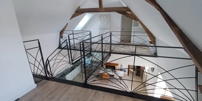 Escalier limon central 1/4 tournant débillardé, marches en chêne rustique sablé, laquage ral 2100 sablé Garde corps poteaux plats, remplissage lisses D.10 cintrées, main courante 40x10, laquage ral 2100 sablé Ossature en UPN, remplissage en dalle de verre clair, laquage de l'ossature ral noir 2100 sablé 72170 SEGRIE