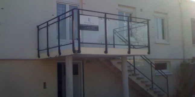 Garde corps de balcon, poteaux plats, remplissage en vitrage trempé, fixation sur pinces, main courante D.40, laquage ral 9005.