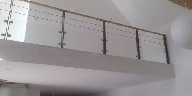 Garde corps en acier, poteaux plats, 2 lignes de câble, soubassement en vitrage clair 44/2 JPP, fixation sur pinces, main courante 50x30 mm en bois.
