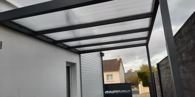Carport en aluminium Ossature en tube carré aluminium, remplissage en polycarbonate alvéolaire 16mm, bandeau de pourtour et chéneau pour renvoi d'eau intégrée dans la traverse, laquage 7016 Fine Texture. 53600 EVRON